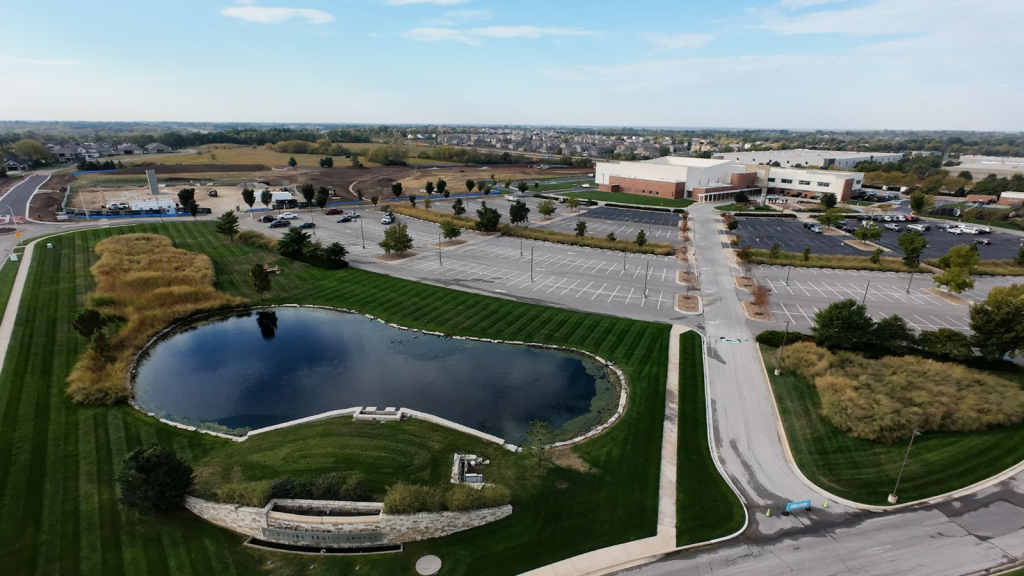 Aerial drone photograph of a commercial real estate property in Lenexa, Kansas, showcasing the building exterior and surrounding parking lot in the Kansas City metro area.