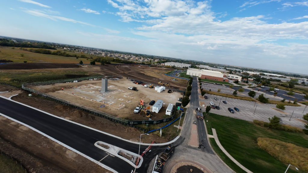 Aerial drone photograph showing a construction site under active development with workers, heavy equipment, and materials for inspection and site monitoring.