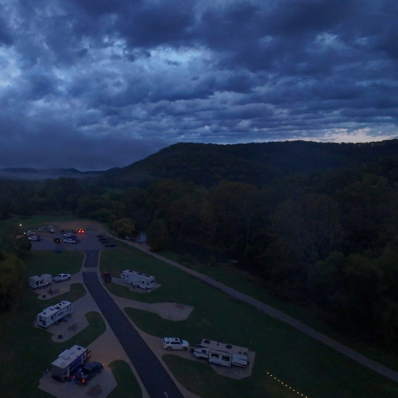 Aerial drone photograph of a dramatic sunset with blue sky and clouds over Roaring River State Park campground in Missouri, captured by Reel Drone Rangers.